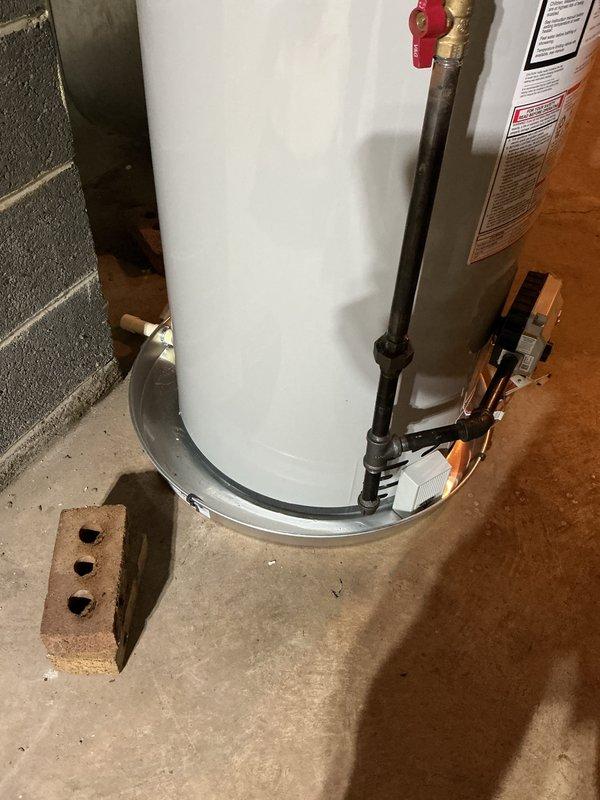 Completed installation of 40-gallon short water heater in basement utility area. Installed new chimney liner and galvanized venting system with proper connections to existing flue. Connected hot and cold water supply lines using copper piping with compression fittings, installed temperature and pressure relief valve with discharge pipe, and positioned unit on metal drip pan per code requirements. Verified all connections for proper operation and tested unit for leaks.
