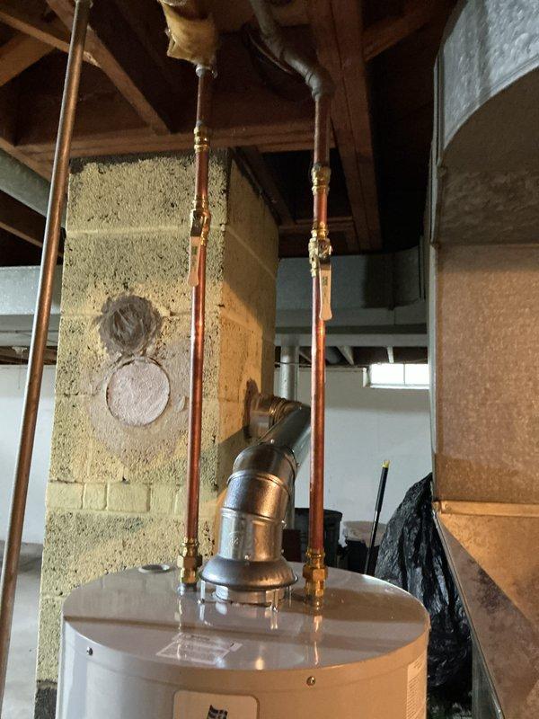 Completed installation of 40-gallon short water heater in basement utility area. Installed new chimney liner and galvanized venting system with proper connections to existing flue. Connected hot and cold water supply lines using copper piping with compression fittings, installed temperature and pressure relief valve with discharge pipe, and positioned unit on metal drip pan per code requirements. Verified all connections for proper operation and tested unit for leaks.