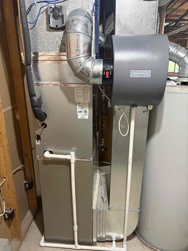 Completed annual cooling system tune-up and furnace maintenance on residential HVAC system. Performed comprehensive inspection of indoor furnace unit with integrated Honeywell Home humidifier and outdoor condensing unit. Inspected all electrical connections, ductwork, condensate drain lines, and system controls. Noted exterior coil surfaces on outdoor unit showing accumulation of dirt, pollen, and debris on protective mesh screening with visible moisture streaking. Verified proper operation of all system components and confirmed unit functionality for continued seasonal use.