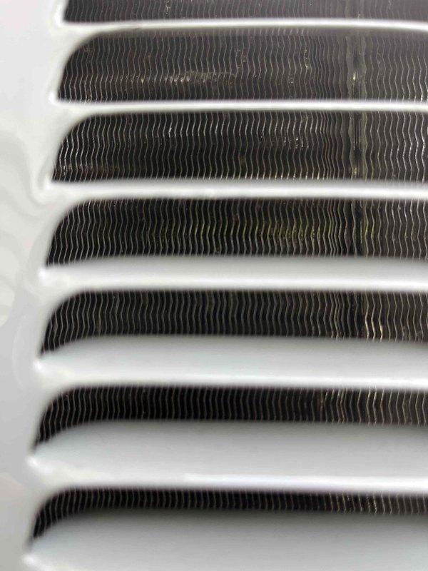 Completed annual cooling system maintenance on EnergiAir unit under active warranty coverage. Performed comprehensive inspection of evaporator coil assembly, noting minor dust accumulation on fin surfaces but overall satisfactory heat exchange component condition. Inspected return air grille and documented moderate dust and debris buildup between louvers and in recessed areas, typical of normal system operation. All photographic documentation captured for warranty and maintenance records.