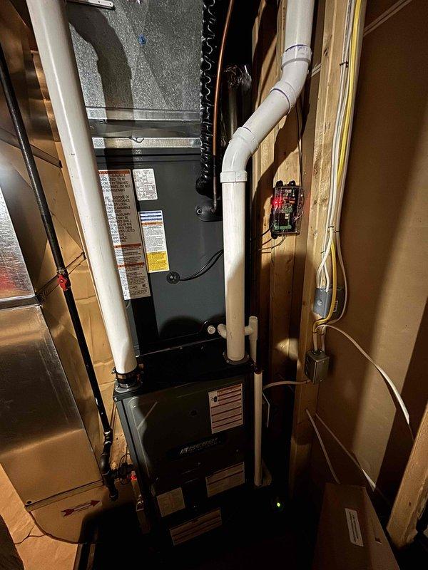 Completed full air conditioning system replacement including outdoor condensing unit and indoor air handler/furnace components. Installed new equipment in basement utility area with proper PVC drainage lines, electrical connections, and ductwork integration. Positioned outdoor unit on concrete pad with appropriate clearances, connected refrigerant lines, and verified all electrical disconnects and controls are properly installed and operational.