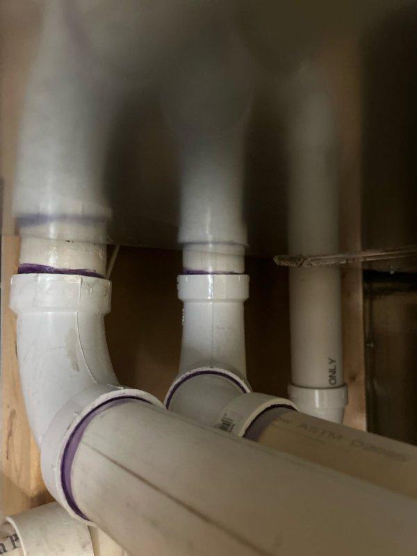 Responded to a plumbing leak in the utility room of a residential property. Upon arrival, inspected the area and located the source of the leak in the PVC drainage piping system. The leak was present at a joint connection where primer and solvent cement had failed, allowing water seepage for approximately three days. 

Assessed the affected plumbing configuration, which included multiple vertical and horizontal PVC pipe runs with elbow joints in a confined utility space near the HVAC system. Verified the leak location and determined that the joint required proper re-sealing. Applied appropriate PVC primer and cement to secure the connection and eliminate the leak. Tested the repair by running water through the system to confirm no further seepage was occurring.

Documented the repair with photographs showing the before condition and the piping layout for service records. The repair was completed successfully with no additional leaks detected at the time of departure.