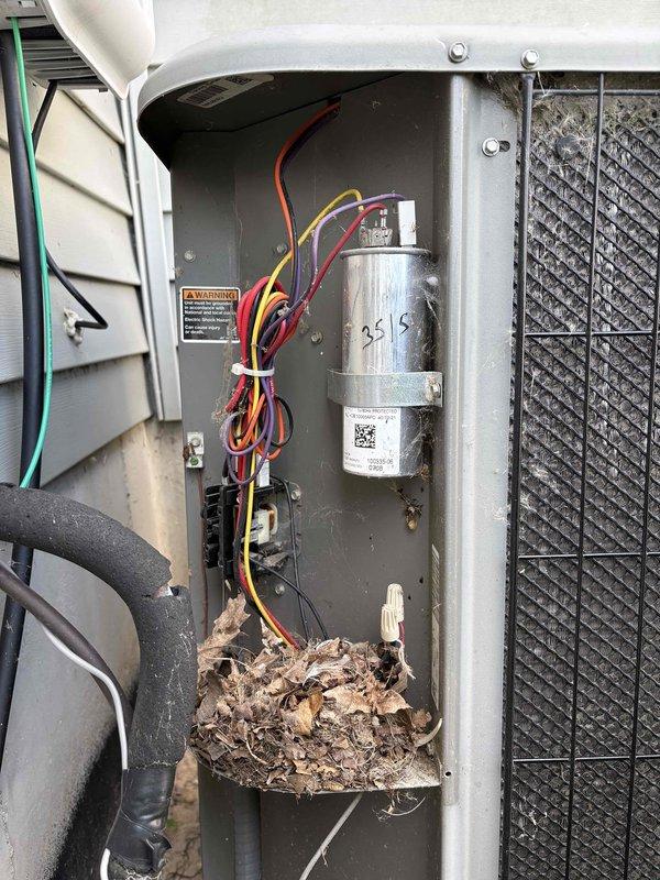 # AC Repair - No Cooling

Responded to service call for 16-year-old Lennox air conditioning system not producing cold air throughout residence. Upon arrival, performed diagnostic inspection of outdoor condensing unit.

Opened electrical compartment and discovered heavy accumulation of organic debris (leaves, twigs, plant material) in bottom of unit housing, indicating prolonged outdoor exposure without adequate maintenance. Removed debris to prevent potential airflow restriction and fire hazard.

Inspected electrical components and identified severe corrosion on contactor relay assembly, showing brown and reddish deterioration patterns consistent with moisture exposure. Corrosion was affecting electrical connectivity and preventing proper compressor operation, which explained complete loss of cooling capacity.

Noted 25/5 MFD dual run capacitor present in system with visible labeling. Evaluated all wire connections including red, yellow, orange, purple, and black conductors. Observed p