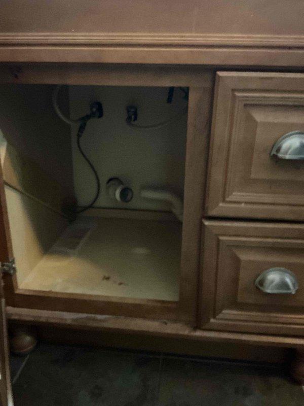 Provided project estimate for sump pump installation in residential property. Additionally assessed bathroom vanity faucet with significant rust corrosion on fixtures and basin, documenting existing plumbing configuration including P-trap assembly and under-sink connections for repair recommendations.