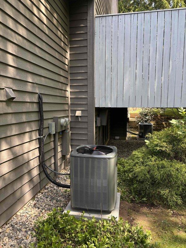 Completed full air conditioning system replacement at residential property. Removed existing AC unit and installed new gray condenser unit on prepared concrete pad with proper gravel drainage base. Ran new refrigerant lines from condenser to house exterior, securing lines along wall with appropriate fasteners. Installed electrical disconnect box and conduit on exterior siding per code requirements. Connected unit to existing electrical service at meter location. Performed system startup, verified proper refrigerant charge levels, tested electrical connections, and confirmed optimal airflow and cooling performance. System operating within manufacturer specifications upon completion.