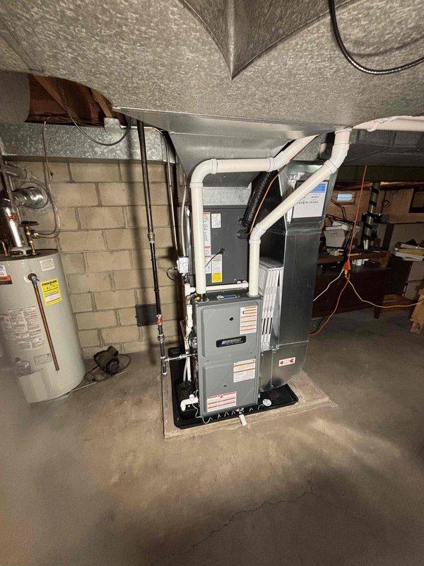 Completed full HVAC system installation in basement mechanical room, including new furnace unit and air handler. Furnace positioned on concrete pad with proper PVC venting routed upward, copper refrigerant lines run and connected, and all electrical wiring completed. Air handler installed against concrete block wall with associated ductwork connections, proper clearances maintained for service access. All units secured, labeled, and tested for proper operation per manufacturer specifications.