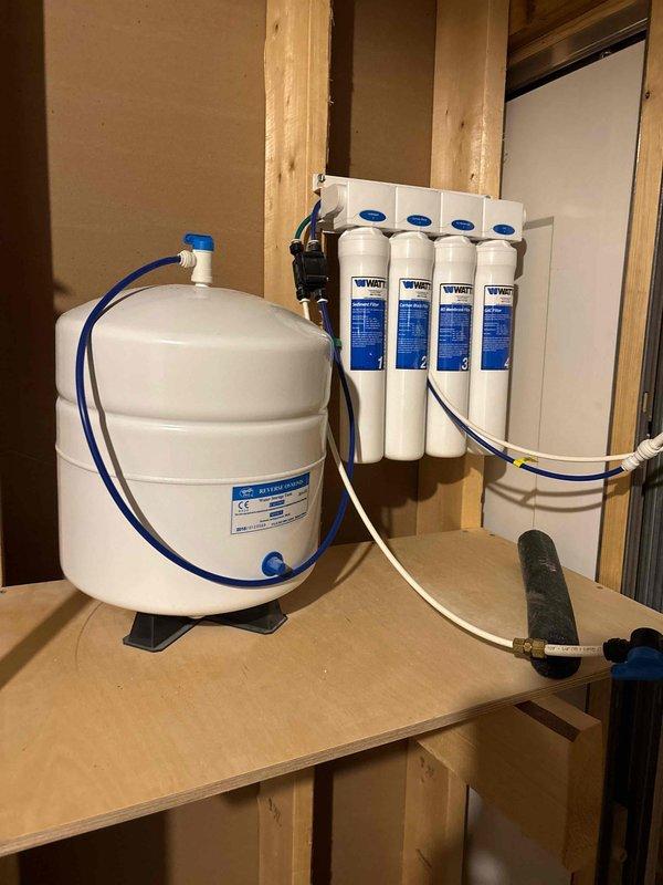 Responded to complaint of continuous water running sound in kitchen drain. Diagnosed issue as faulty reverse osmosis system with water bypassing storage tank and draining directly into drain line. Isolated problem by shutting off water supply to RO unit, which eliminated the sound. Inspected four-stage filtration system and pressurized storage tank, verified proper connections and tubing routing, and restored normal operation to the reverse osmosis unit.