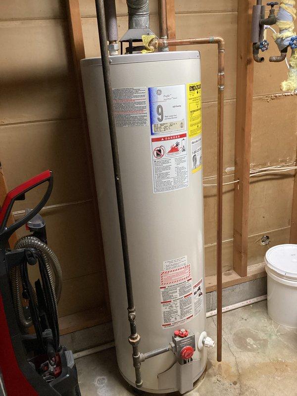 Responded to no hot water call where 14+ year old water heater was found leaking heavily from the bottom tank. Upon arrival, confirmed water supply and pilot light had already been shut off by customer. Inspected unit and documented existing installation showing standard atmospheric gas water heater with copper supply lines, relief valve piping, and metal exhaust venting. Observed water damage on concrete floor and confirmed active leak from tank base, indicating internal tank failure typical of units beyond expected service life. Photographed installation configuration including plumbing connections, shut-off valves, venting arrangement, and overall placement in unfinished basement utility area for replacement planning purposes. Confirmed unit is not located in mobile or manufactured home. Advised that tank replacement is necessary due to catastrophic tank failure and age of existing equipment.