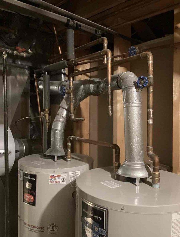 Responded to water heater leak complaint and performed comprehensive inspection of the system. Upon arrival, identified active leak from water heater tank requiring unit replacement. Documented existing dual water heater installation with associated copper piping network, blue-handled shut-off valves, and connection points. Photographed current system configuration including ductwork, plumbing infrastructure, and mechanical components in the utility space. Provided detailed replacement quote to customer for new water heater installation including necessary materials and labor.