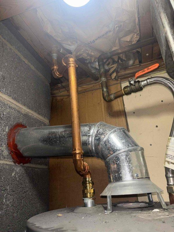 Responded to water heater service call and performed comprehensive inspection of Rheem Performance Plus residential unit located in basement mechanical room. Documented existing installation including copper supply lines, pressure relief valve connections, gas control assembly, and proper drip pan placement. Inspected accessible plumbing connections in crawl space area, including vertical copper piping with brass fittings and galvanized ductwork with support hardware. Verified water heater safety labels present and legible, including manufacturer specifications and warning placards. All components photographed for service records and customer documentation.