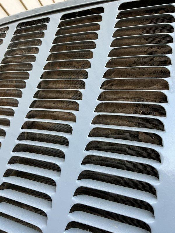 Completed annual cooling system maintenance on 2015 EnergiAir unit under active warranty coverage through July 2033. Inspected and photographed exterior grille showing significant dust and debris accumulation on louvers, as well as condenser coil assembly with minor surface moisture present. Performed standard tune-up procedures including cleaning, system evaluation, and documentation of current operating condition.
