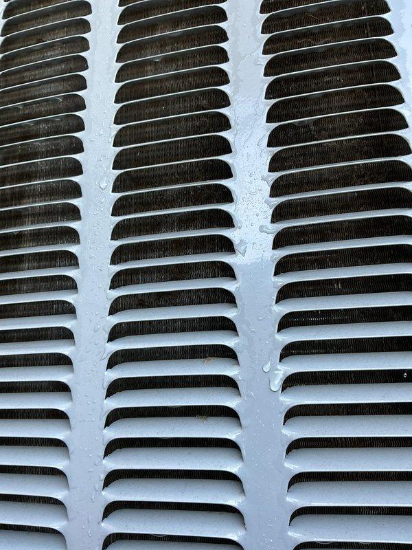 Completed annual cooling system maintenance on 2015 EnergiAir unit under active warranty coverage through July 2033. Inspected and photographed exterior grille showing significant dust and debris accumulation on louvers, as well as condenser coil assembly with minor surface moisture present. Performed standard tune-up procedures including cleaning, system evaluation, and documentation of current operating condition.
