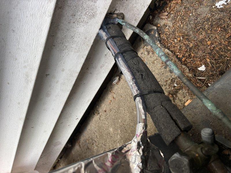 Responded to cooling system issue on 13-year-old Goodman unit. Replaced damaged electrical wire that had been previously spliced with tape, requiring drywall access for proper repair. Secured new wiring to manufacturer specifications and restored system to normal operation. Documented existing exterior line set installation and foundation penetration points showing typical weathering. Unit tested and confirmed operational upon completion.