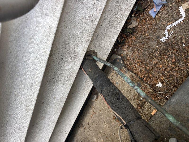 Responded to cooling system issue on 13-year-old Goodman unit. Replaced damaged electrical wire that had been previously spliced with tape, requiring drywall access for proper repair. Secured new wiring to manufacturer specifications and restored system to normal operation. Documented existing exterior line set installation and foundation penetration points showing typical weathering. Unit tested and confirmed operational upon completion.