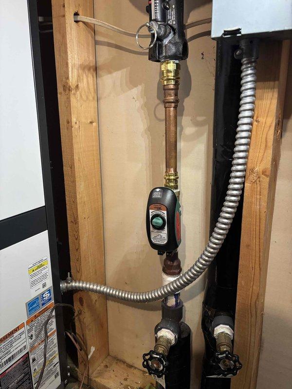 Responded to service call for 9-year-old Bosch geothermal unit continuously running water regardless of heating or cooling demand. Upon inspection, identified failed flow center assembly with malfunctioning zone valve causing constant water circulation through the system. Photographed existing plumbing configuration showing corroded copper piping, backflow preventer, expansion tank, and isolation valves within the mechanical room. Recommended replacement of defective flow control components to restore proper system operation and prevent unnecessary water flow and energy consumption.