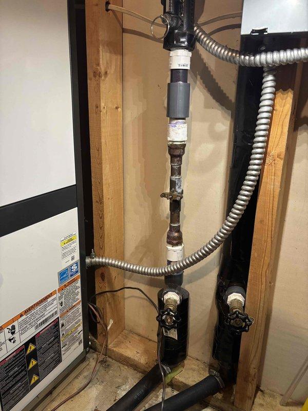 Responded to service call for 9-year-old Bosch geothermal unit continuously running water regardless of heating or cooling demand. Upon inspection, identified failed flow center assembly with malfunctioning zone valve causing constant water circulation through the system. Photographed existing plumbing configuration showing corroded copper piping, backflow preventer, expansion tank, and isolation valves within the mechanical room. Recommended replacement of defective flow control components to restore proper system operation and prevent unnecessary water flow and energy consumption.