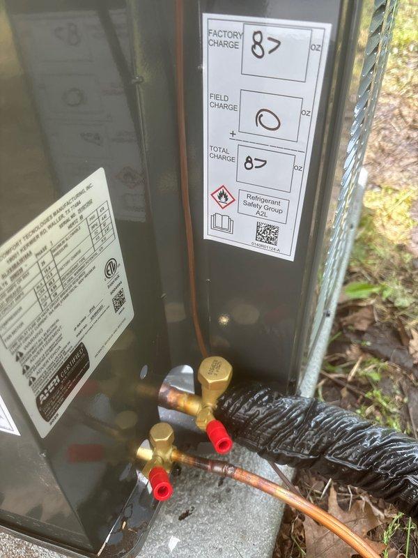 Completed full air conditioning system replacement at residential property. Installed new outdoor condenser unit on concrete pad against exterior wall with proper electrical disconnect box and refrigerant line connections through vinyl siding. System charged with 87 oz factory refrigerant charge per manufacturer specifications, with service valves properly installed and capped for future maintenance access. All electrical conduit and copper refrigerant lines secured to exterior wall, unit positioned for optimal airflow and serviceability adjacent to elevated deck structure.
