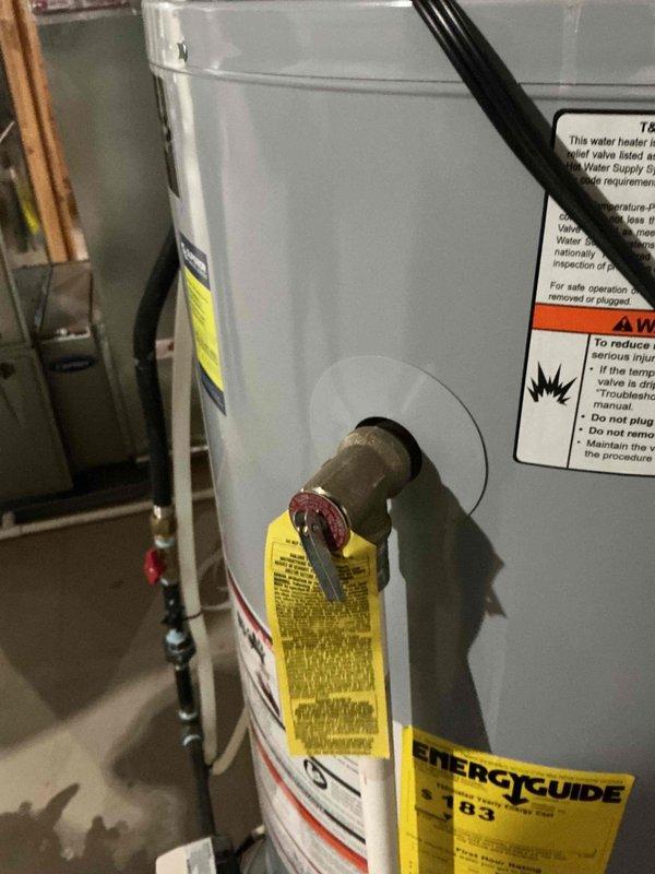 Responded to water heater leak at valve connection on 5-year-old Lochinvar unit. Upon inspection, identified active leak at side-mounted valve fitting with corroded drain pan beneath unit, as evidenced by visible water pooling on concrete floor. Documented existing conditions showing deteriorated pan requiring replacement and compromised valve assembly needing immediate attention to prevent further water damage.