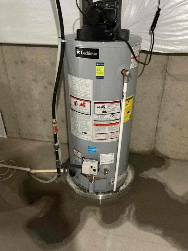 Responded to water heater leak at valve connection on 5-year-old Lochinvar unit. Upon inspection, identified active leak at side-mounted valve fitting with corroded drain pan beneath unit, as evidenced by visible water pooling on concrete floor. Documented existing conditions showing deteriorated pan requiring replacement and compromised valve assembly needing immediate attention to prevent further water damage.