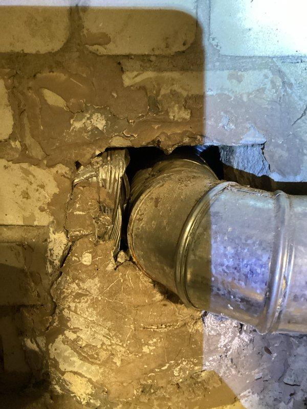 Responded to customer concern regarding questionable water heater ventilation discovered during basement remodeling. Inspected 9-year-old State ProLine water heater and assessed vent pipe penetration through concrete block wall. Found deteriorated sealing material around vent connector with significant cracking, separation, and crumbling of foam/sealant at wall penetration point, indicating substandard previous installation requiring correction before drywall installation proceeds.