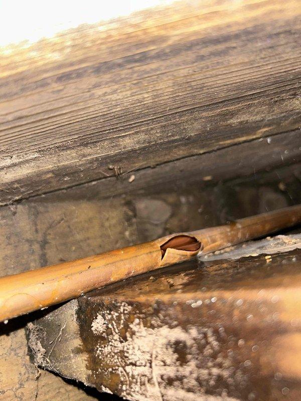 Responded to plumbing leak emergency involving a burst copper pipe located underneath deck structure. Upon inspection, identified significant split in copper water line running through crawl space beneath wooden decking, with visible moisture damage to surrounding wooden joists and beams. The pipe failure likely resulted from freeze damage during winter months. Successfully repaired the damaged section by cutting out the compromised copper pipe and installing a brazed coupling joint with proper soldering technique. Verified repair integrity and restored water service to the affected line.