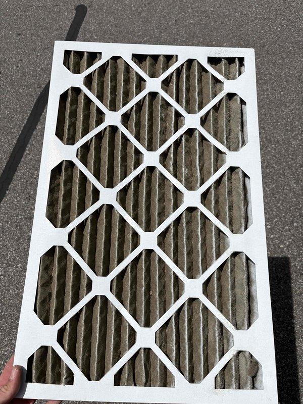 Responded to no cooling condition affecting entire residential home with 4-5 year old air conditioning system. Upon arrival, inspected outdoor condensing unit (Goodman model N4A342AKN300, manufactured July 2020) and documented equipment nameplate specifications. Discovered severely restricted air filter with heavy dust and debris accumulation blocking airflow. Removed and photographed dirty pleated filter showing significant contamination that was inhibiting proper system operation and airflow across evaporator coil. Replaced filter with new unit to restore adequate airflow. Verified system specifications including 5.84 lb factory refrigerant charge, 208-230V single-phase power supply, and TXV metering device. System returned to normal cooling operation following filter replacement. Recommended regular filter maintenance every 30-90 days depending on household conditions to prevent future airflow restrictions and maintain optimal system performance.