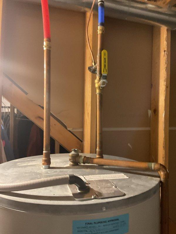 Provided estimate for water heater replacement in residential basement utility area. Assessed existing water heater installation with copper supply piping, brass fittings, and shut-off valve configuration. Documented current unit condition and plumbing connections including hot and cold water lines with insulated sleeves, T-junction piping arrangement, and flexible drain line. Photographed installation for quote preparation purposes.