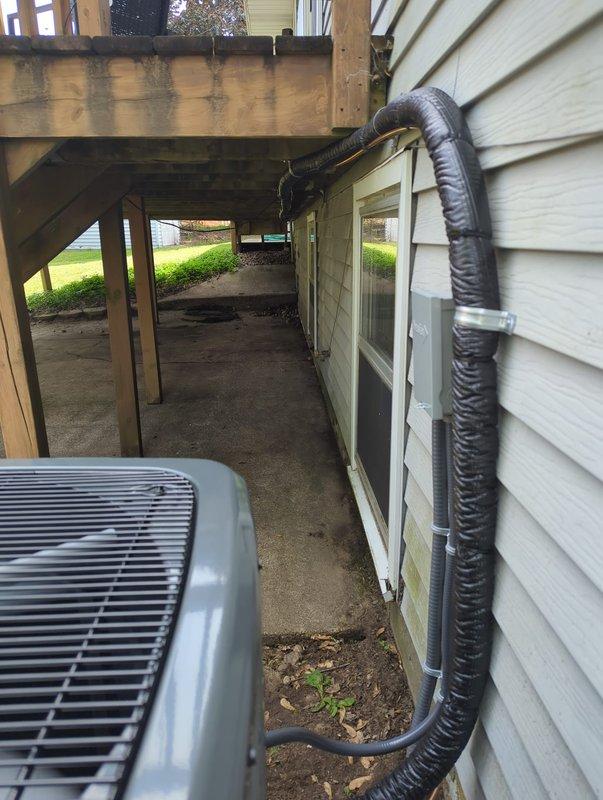 Completed full air conditioning system replacement at residential property. Installed new condensing unit in exterior walkway beneath elevated deck structure, positioning equipment on concrete pad with proper clearances. Connected refrigerant lines with appropriate insulation, installed service valves, and secured condensate drainage line to building exterior wall. Verified all refrigerant circuit connections, charging specifications, and system operation per manufacturer requirements.