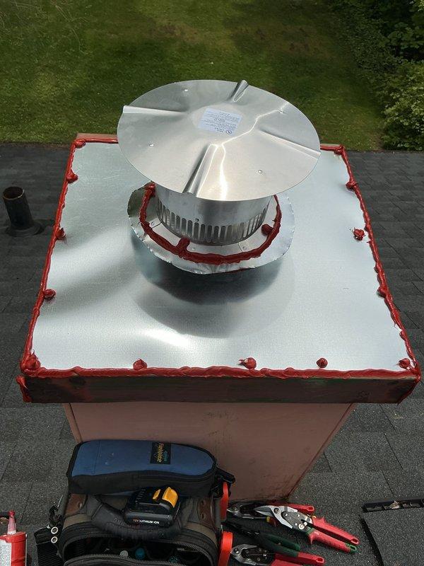 Completed installation of new chimney liner and venting system for residential HVAC equipment. Removed existing deteriorated flue components and installed Type B double-wall vent pipe from Goodman furnace through roof penetration. Fabricated and installed proper vent termination with approved rain cap assembly on roof, sealed with high-temperature red silicone caulking around white storm collar and flashing base. Connected vent system to furnace cabinet with proper clearances and secured all joints per manufacturer specifications. Verified draft operation and confirmed no exhaust leaks throughout entire vent run. All work completed to current mechanical code requirements for safe combustion appliance venting.