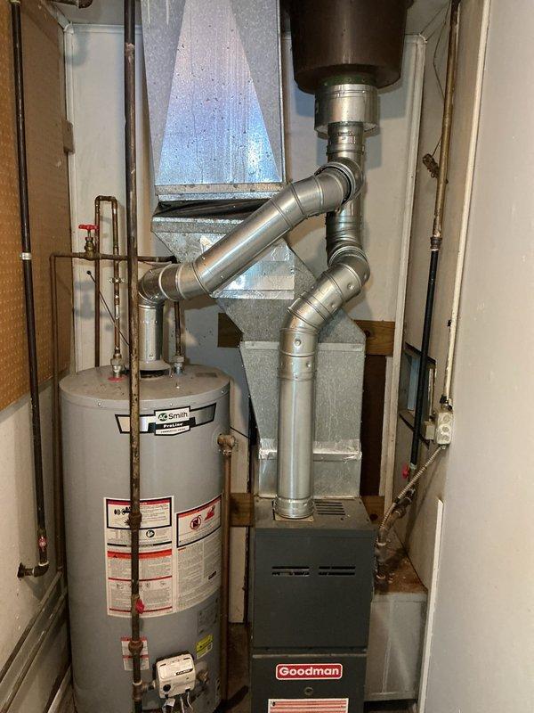 Completed installation of new chimney liner and venting system for residential HVAC equipment. Removed existing deteriorated flue components and installed Type B double-wall vent pipe from Goodman furnace through roof penetration. Fabricated and installed proper vent termination with approved rain cap assembly on roof, sealed with high-temperature red silicone caulking around white storm collar and flashing base. Connected vent system to furnace cabinet with proper clearances and secured all joints per manufacturer specifications. Verified draft operation and confirmed no exhaust leaks throughout entire vent run. All work completed to current mechanical code requirements for safe combustion appliance venting.