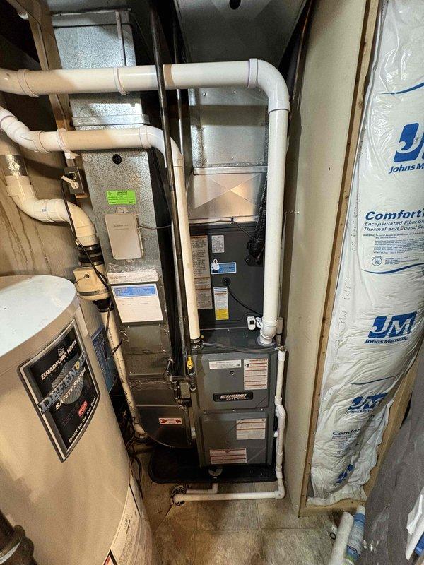 Completed full HVAC system installation including new furnace and air conditioning unit. Installed dark-colored condensing unit on concrete pad against exterior wall with proper clearances and mounted new gas furnace in basement mechanical room with complete PVC venting system, condensate drainage lines, and proper ductwork connections. All equipment positioned per manufacturer specifications, system tested and operational, with financing documentation processed through Michigan Saves program.