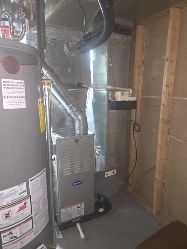 Completed full furnace replacement in basement utility area, installing new Carrier brand unit with proper ductwork connections. Connected rigid metal supply ductwork and flexible return ducting to ensure proper airflow throughout the system. Supplied and positioned three new pleated air filters at equipment base for future maintenance use.