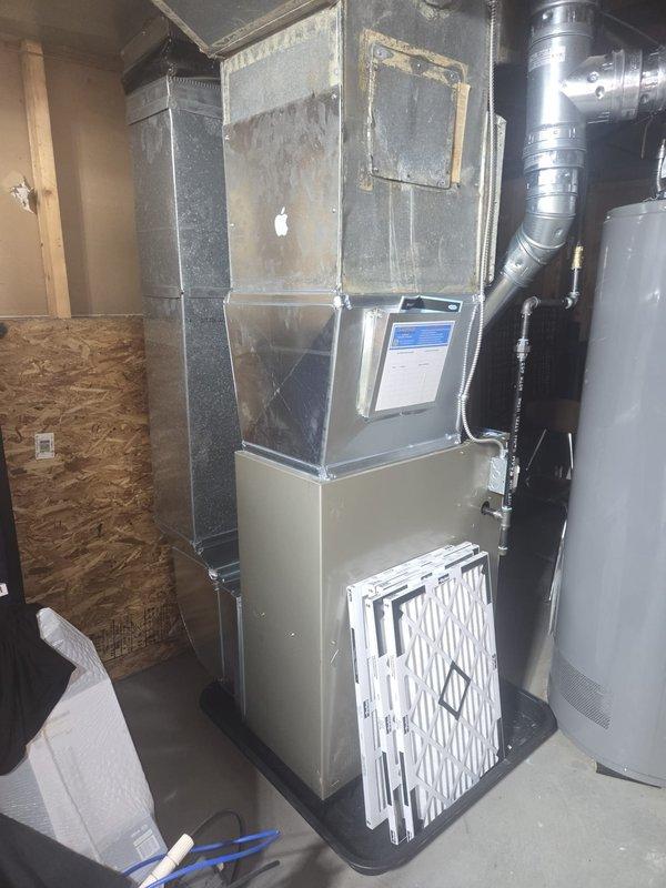 Completed full furnace replacement in basement utility area, installing new Carrier brand unit with proper ductwork connections. Connected rigid metal supply ductwork and flexible return ducting to ensure proper airflow throughout the system. Supplied and positioned three new pleated air filters at equipment base for future maintenance use.