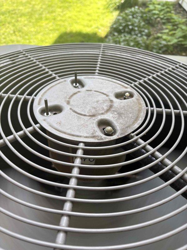 Responded to no cool complaint on 19-year-old Carrier residential AC system. Upon arrival, unit was operational but not cooling adequately. Performed visual inspection of outdoor condenser unit, documenting fan assembly and guard condition. Fan guard and blades showed normal wear and debris accumulation consistent with outdoor exposure. Captured diagnostic photos of condenser fan assembly showing intact protective guard with concentric wire rings, central hub mounting plate, and operational fan blades. Unit components appeared structurally sound with typical dust and environmental buildup. Recommended follow-up service for complete system diagnostics to identify cooling efficiency issue.