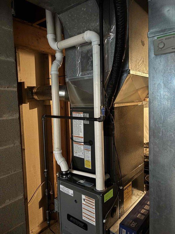 Completed full air conditioning system replacement and installation in residential basement location. New HVAC unit installed with proper venting system including white PVC piping with multiple connections and drainage components, secured with metal support brackets. All ductwork connected to existing infrastructure, system tested and operational, financing documentation processed and secured through Michigan Saves program.