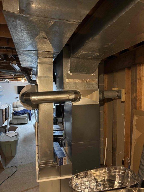 Completed full air conditioning system replacement and installation in residential basement location. New HVAC unit installed with proper venting system including white PVC piping with multiple connections and drainage components, secured with metal support brackets. All ductwork connected to existing infrastructure, system tested and operational, financing documentation processed and secured through Michigan Saves program.