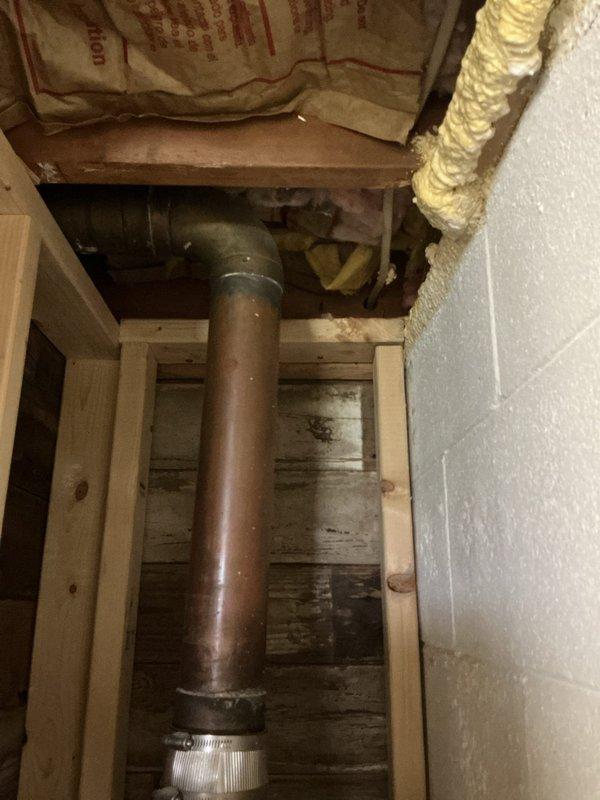 Responded to service call for non-operational sump pump and outdoor faucet replacement. Upon inspection, assessed the sump pump discharge piping system running through the ceiling cavity and attic space. Documented existing metal discharge pipe configuration and routing through wooden framing members, noting aged galvanized ductwork and surrounding building infrastructure. Identified issues with the sump pump system and provided recommendations for repair to restore proper functionality and prevent potential water damage.