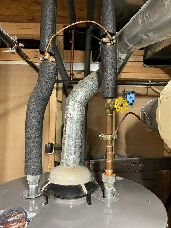 Conducted comprehensive assessment of existing 20-year-old central heating and air conditioning system for replacement estimate. Evaluated current furnace and AC unit configuration, documented existing ductwork connections, plenum assembly, and venting system. Photographed water heater installation with associated plumbing connections, insulated supply lines, and gas shut-off valve for reference during future HVAC system replacement planning.