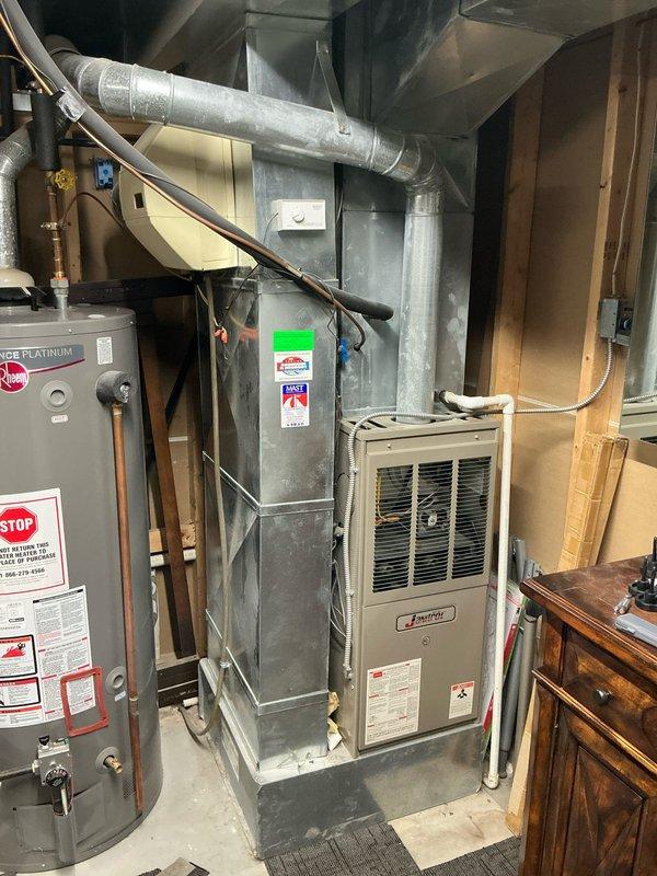 Conducted comprehensive assessment of existing 20-year-old central heating and air conditioning system for replacement estimate. Evaluated current furnace and AC unit configuration, documented existing ductwork connections, plenum assembly, and venting system. Photographed water heater installation with associated plumbing connections, insulated supply lines, and gas shut-off valve for reference during future HVAC system replacement planning.