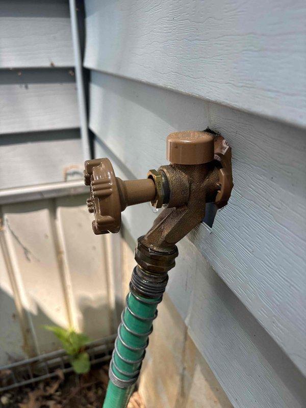 Responded to a plumbing leak at an outdoor hose bib mounted on exterior wooden siding. Upon arrival, identified active leak near the spigot connection point on the brass valve assembly. Repaired the leaking hose bib by replacing worn internal components and ensuring proper seal at all connection points. Tested the fixture under full water pressure to confirm leak was eliminated and verified proper operation of the valve handle and threading. System restored to full functionality with no further water discharge detected.