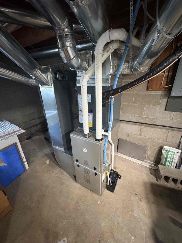 Completed add-on air conditioning system installation to existing forced-air heating system. Installed outdoor condensing unit on concrete pad with proper clearances from building exterior and electrical disconnect. Ran refrigerant lines from outdoor unit through building envelope to basement mechanical room. Integrated evaporator coil with existing furnace and connected to supply ductwork. Installed necessary electrical connections, tested system operation, and verified proper airflow and refrigerant charge levels.