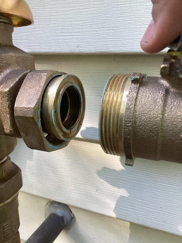Responded to exterior plumbing leak at outdoor hose bib assembly with backflow preventer. Upon arrival, found active leak at brass fitting connection that had been temporarily left incomplete during previous fall repair when outdoor pipe burst. The irrigation system had since been reconnected for spring season, allowing for completion of the original repair. Inspected backflow preventer assembly with multiple shut-off valves and confirmed leak isolated to brass threaded connection point. Properly secured and tightened brass fittings with appropriate gasket seal to complete the connection that had been deferred pending irrigation system reactivation. Verified all connections sealed, tested system under pressure, and confirmed no further leakage at exterior water service point.