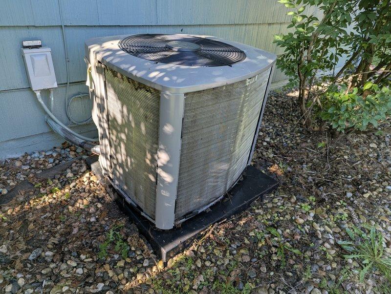 Completed annual cooling maintenance on residential air conditioning system. Unit exterior showed significant accumulation of dirt, dust, and debris on condenser cabinet panels. Performed standard tune-up procedures including system inspection, cleaning of condenser coils, verification of proper refrigerant levels, and testing of electrical components and fan operation. Confirmed unit is operational and ready for cooling season. Documented equipment condition with photographs showing outdoor condenser unit positioned on plastic pad in gravel area with adequate clearance for airflow and service access.