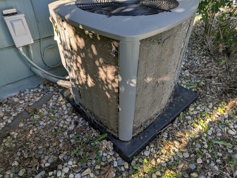 Completed annual cooling maintenance on residential air conditioning system. Unit exterior showed significant accumulation of dirt, dust, and debris on condenser cabinet panels. Performed standard tune-up procedures including system inspection, cleaning of condenser coils, verification of proper refrigerant levels, and testing of electrical components and fan operation. Confirmed unit is operational and ready for cooling season. Documented equipment condition with photographs showing outdoor condenser unit positioned on plastic pad in gravel area with adequate clearance for airflow and service access.