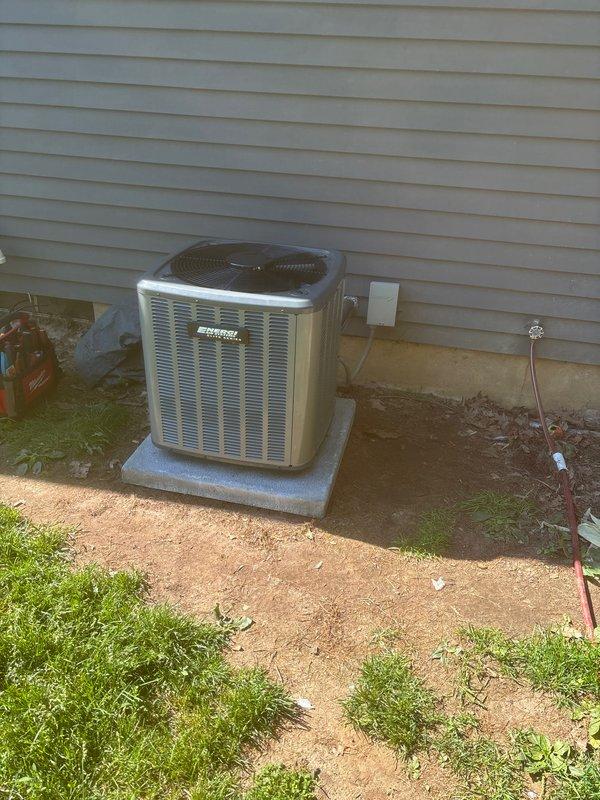 Completed full HVAC system replacement including outdoor condensing unit and indoor air handler. Removed existing equipment and installed new condenser on concrete pad with proper clearances from structure. Unit features protective top grille and side louvers for optimal airflow. Indoor installation includes new air handler positioned above furnace in mechanical room with integrated condensate drainage system using PVC piping, gas line connections, and properly sealed ductwork transitions. All electrical connections completed to code with disconnect box mounted on exterior wall. System tested for proper operation, refrigerant charge verified, and all safety controls confirmed functional.