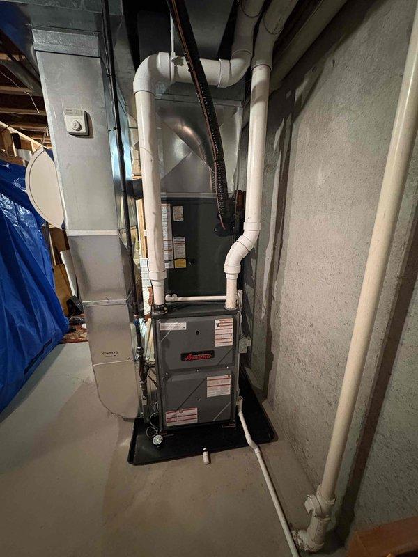 Completed full HVAC system installation including outdoor Amana condensing unit positioned in side yard on concrete paver pad with proper clearances and indoor furnace with air handler in basement mechanical room. Ran refrigerant line set from exterior unit through wall penetration with secure mounting brackets and proper insulation. Installed white PVC condensate drain piping and venting system connected to furnace, routed along basement ceiling to code-compliant termination points. Positioned equipment on protective pads over concrete surfaces. Connected all electrical components, verified proper voltage and amperage to both indoor and outdoor units. Pressure tested refrigerant lines for leaks, evacuated system, and charged to manufacturer specifications. Verified airflow, temperature split, and proper cycling of both heating and cooling modes. All installations meet current building codes and manufacturer requirements for warranty compliance.