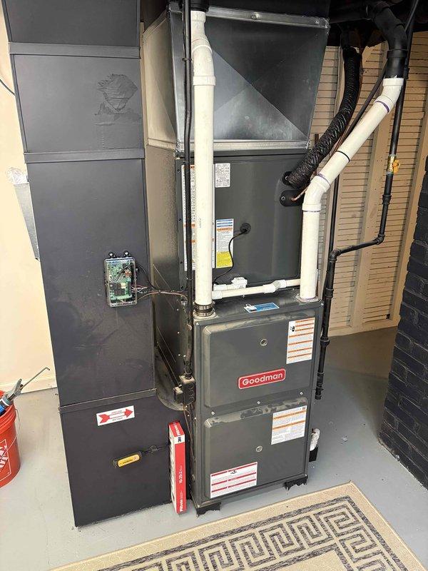 Completed full air conditioning system replacement including outdoor condenser unit installed on concrete pad with proper refrigerant line connections and condensate drainage via white PVC piping. Indoor installation included Goodman furnace with integrated air handler, vertical condensate drain line, and all necessary ductwork connections. System was properly commissioned, tested for operational efficiency, and all components verified for proper function with financing documentation processed through electronic signature platform.
