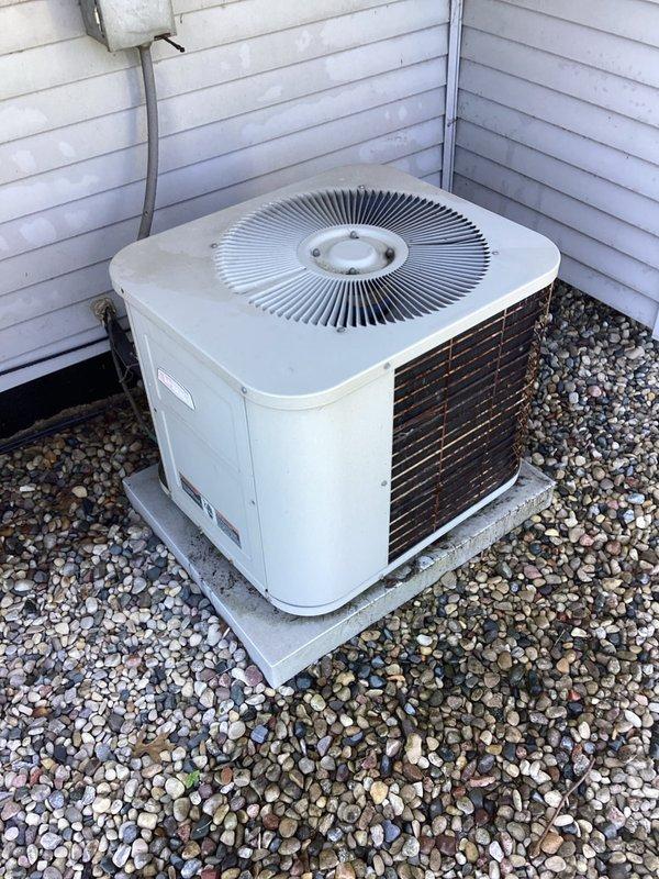Completed annual cooling maintenance on outdoor condensing unit. Performed comprehensive system inspection including visual examination of condenser coil, fan assembly, electrical connections, and refrigerant line sets. Unit appears to be approximately 37 years old with beige metal cabinet and circular top-discharge fan grille. Inspected heat exchanger coil fins showing bronze coloration, confirmed proper mounting on concrete pad with river rock landscaping base. Verified electrical conduit connections and examined base-mounted refrigerant piping, condensate drain line, and associated fittings for proper installation and potential leaks. System showing normal weathering consistent with age but operating within acceptable parameters at time of inspection.