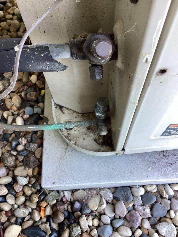 Completed annual cooling maintenance on outdoor condensing unit. Performed comprehensive system inspection including visual examination of condenser coil, fan assembly, electrical connections, and refrigerant line sets. Unit appears to be approximately 37 years old with beige metal cabinet and circular top-discharge fan grille. Inspected heat exchanger coil fins showing bronze coloration, confirmed proper mounting on concrete pad with river rock landscaping base. Verified electrical conduit connections and examined base-mounted refrigerant piping, condensate drain line, and associated fittings for proper installation and potential leaks. System showing normal weathering consistent with age but operating within acceptable parameters at time of inspection.