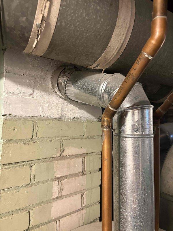 Responded to water leak complaint from 17-year-old ICP heating and cooling system. Upon inspection, found galvanized ductwork and copper piping assembly in basement utility area with visible water staining and mineral deposits on metal surfaces. Examined HVAC infrastructure including water heater connections, copper supply lines with oxidation, and galvanized metal ductwork mounted to masonry wall. Documented existing conditions with photos showing aged equipment, piping connections, and valve assemblies. Customer reported uncertainty about current heating and cooling functionality at time of service call.